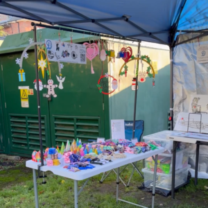 Fidget toy on a stand beside our cot mobile at the market stall