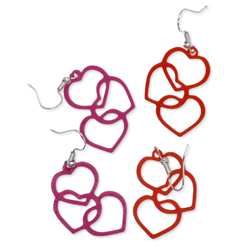 Four earrings shown, each with two interlocking open heart shapes in red or purple and silver hooks, arranged on a white surface. Four earrings shown, each with two interlocking open heart shapes in red or purple and silver hooks, arranged on a white surface. Valentine’s Day jewellery gift